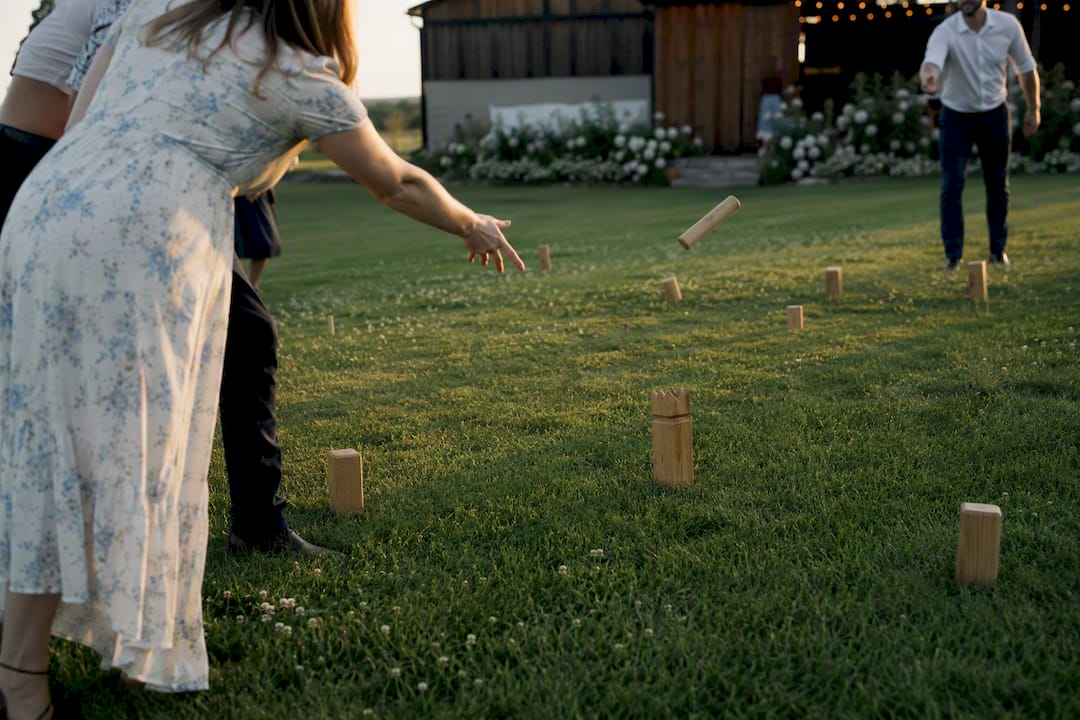 Teams playing Kubbs on wedding lawn