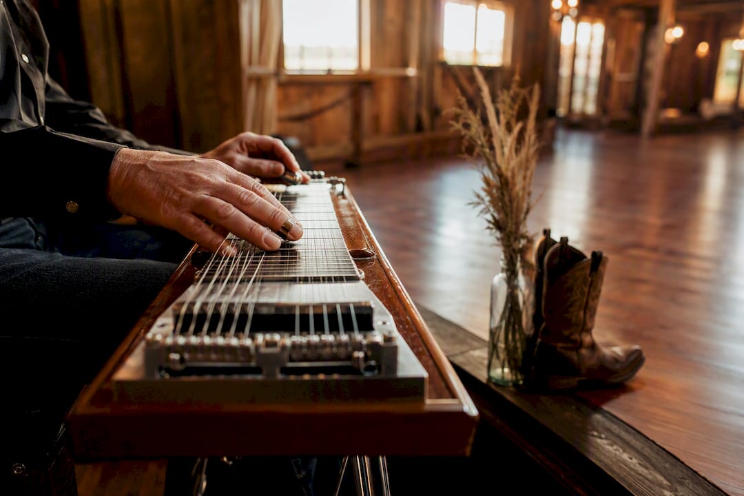 Hands playing steel guitar inside barn