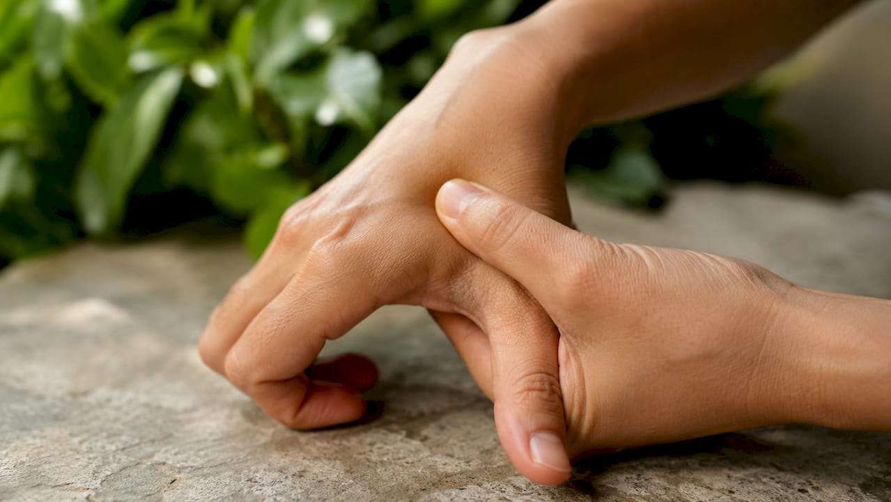 Close-up of hands pressing LI4 acupressure point