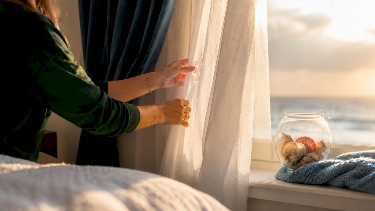 Close-up hands touching sheer fabric of layered drapes