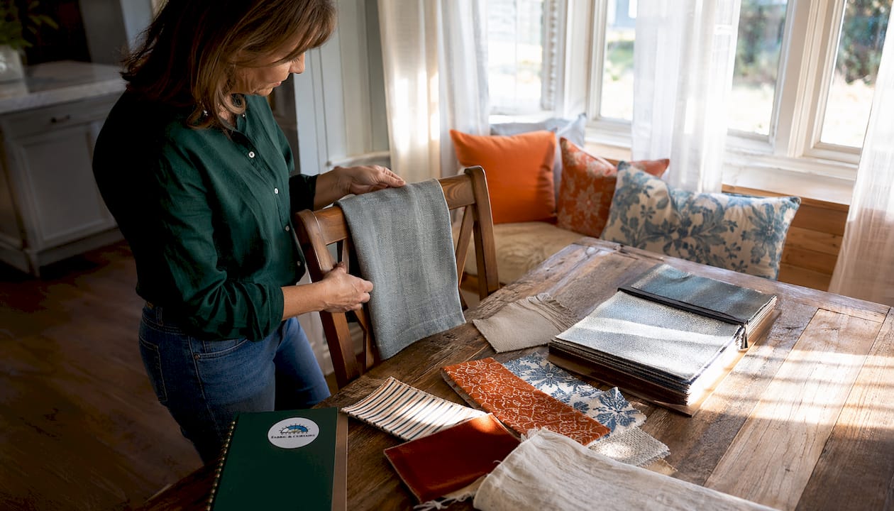 Woman examining upholstery fabric on sofa arm