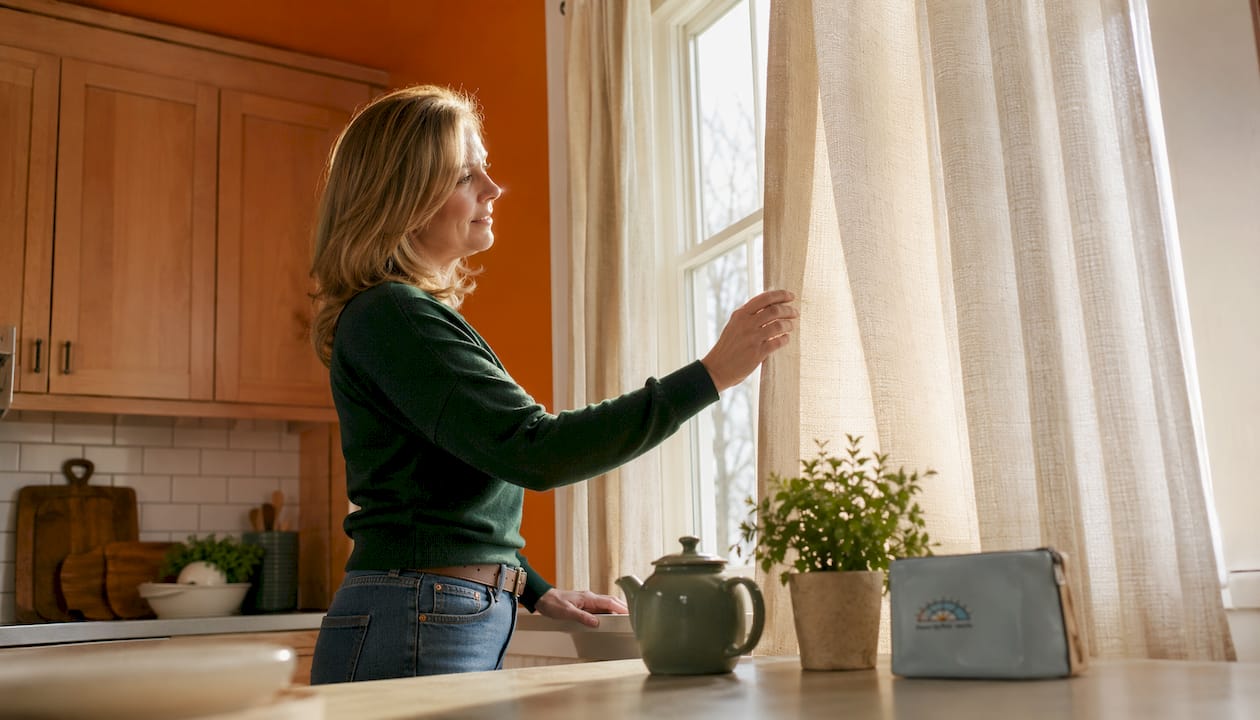 Woman examining thermal curtain panel by window