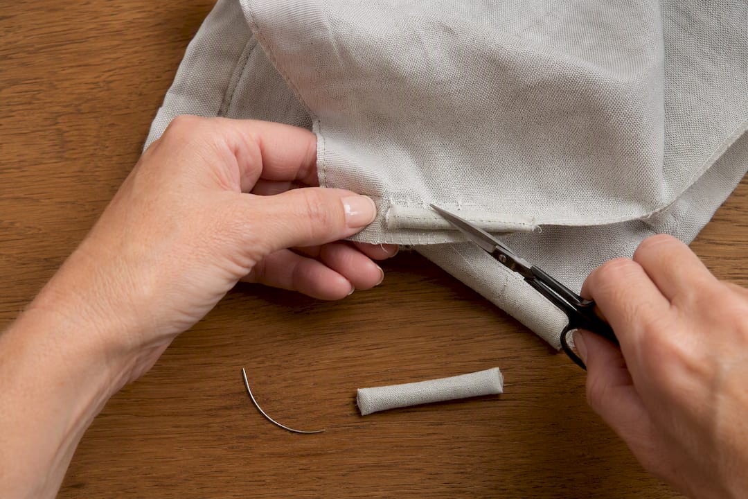 Hands removing stitches around hem weight