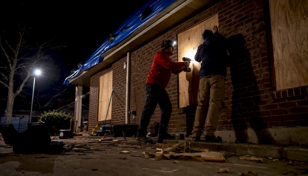 Technicians boarding up fire-damaged house exterior