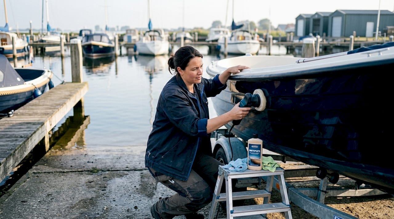 Een vrouw poetst zorgvuldig haar glimmende sloep met een laagje wax.