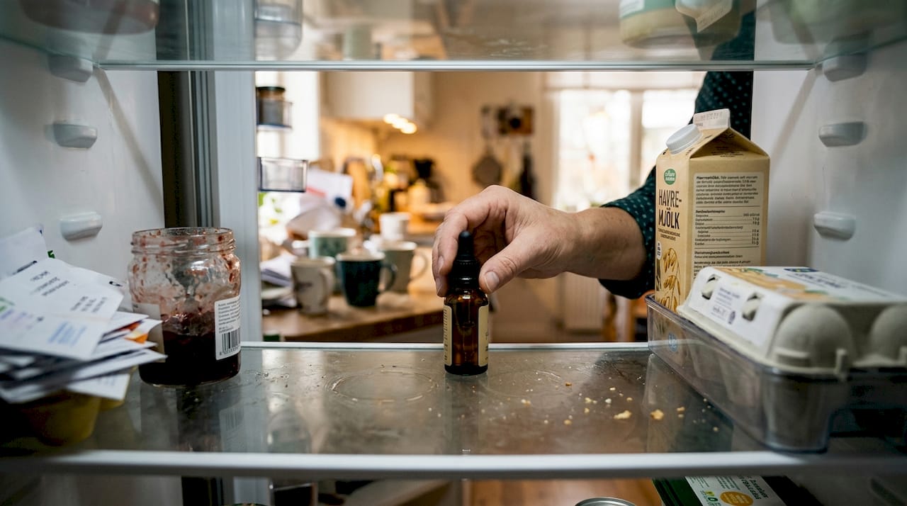 En hand som ställer in CBD-olja i kylskåpet