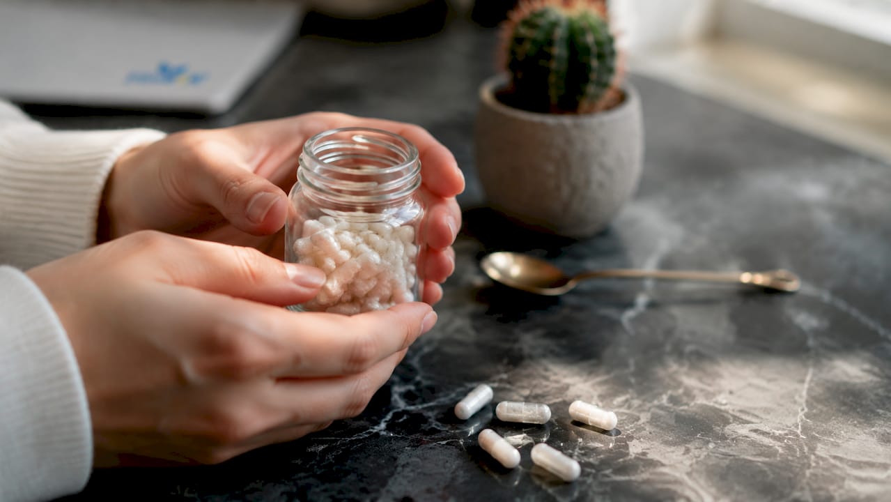 Detaljbild på händer som håller B12-vitaminkapslar