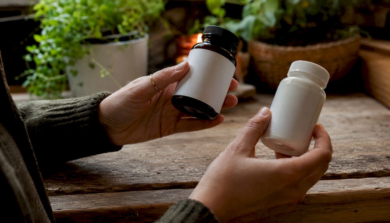 En person står på apoteket og sammenligner forskellige vitaminpiller for at finde den bedste.