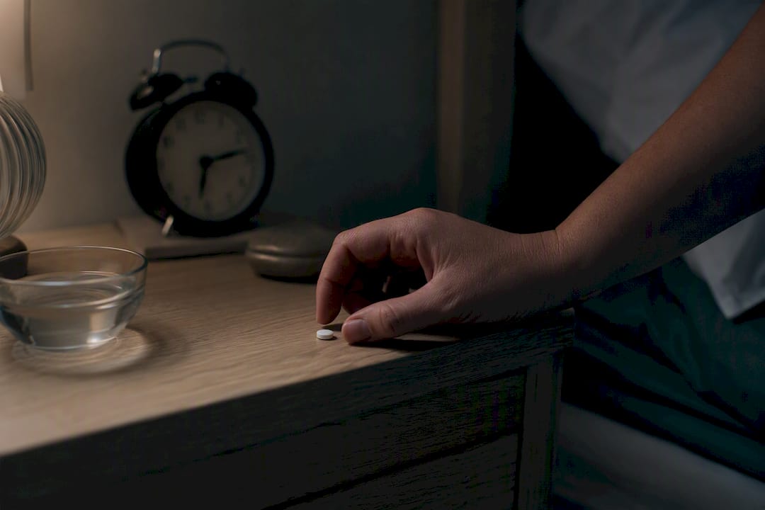 Hand som är på väg att ta melatonin med vatten