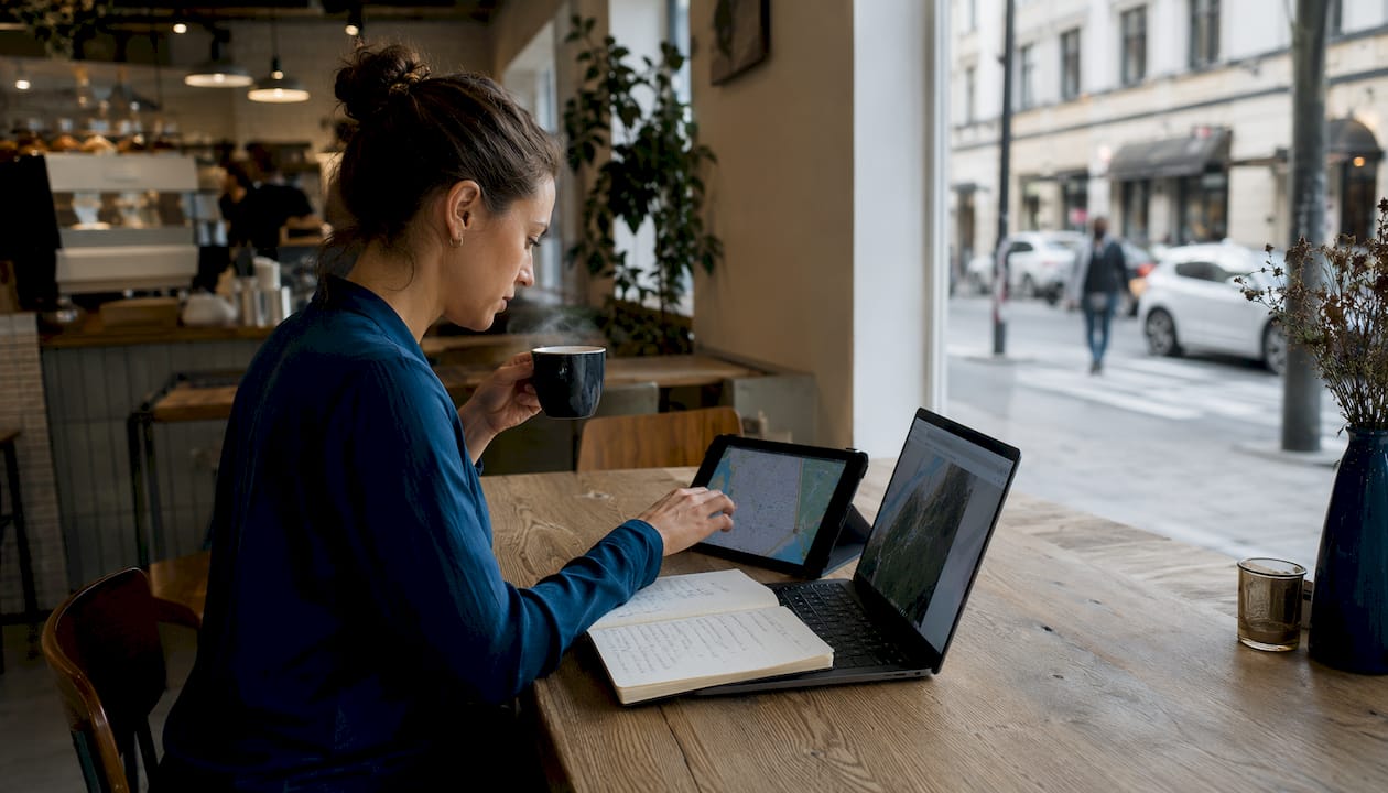 Eine Frau arbeitet am Laptop und nutzt dabei zusätzlich ein Tablet, um digital zu arbeiten.