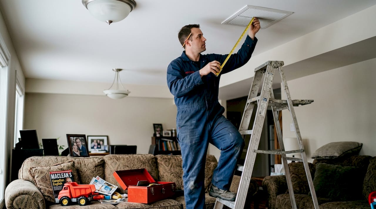 HVAC technician measuring ceiling air vent