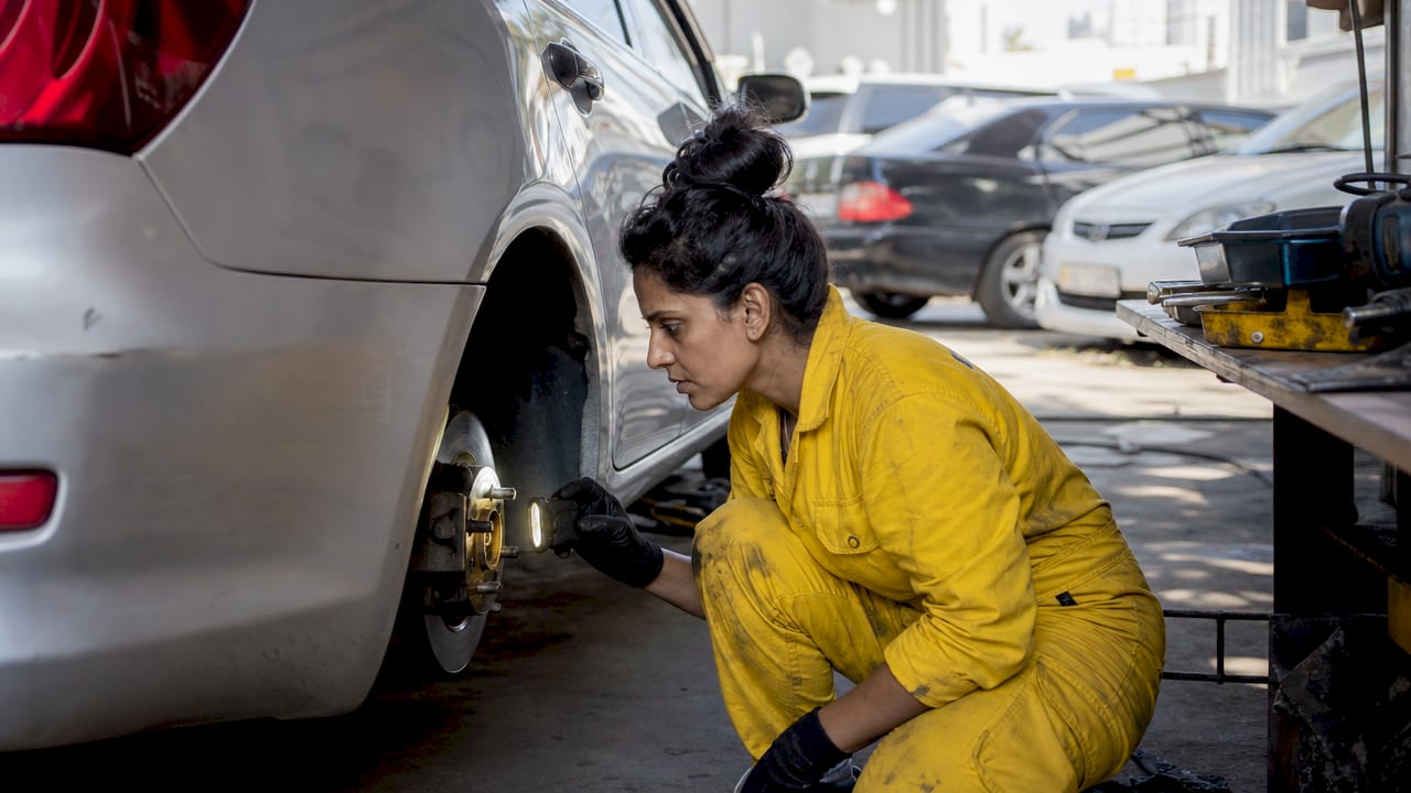 Mechanic inspecting vehicle tire indoors