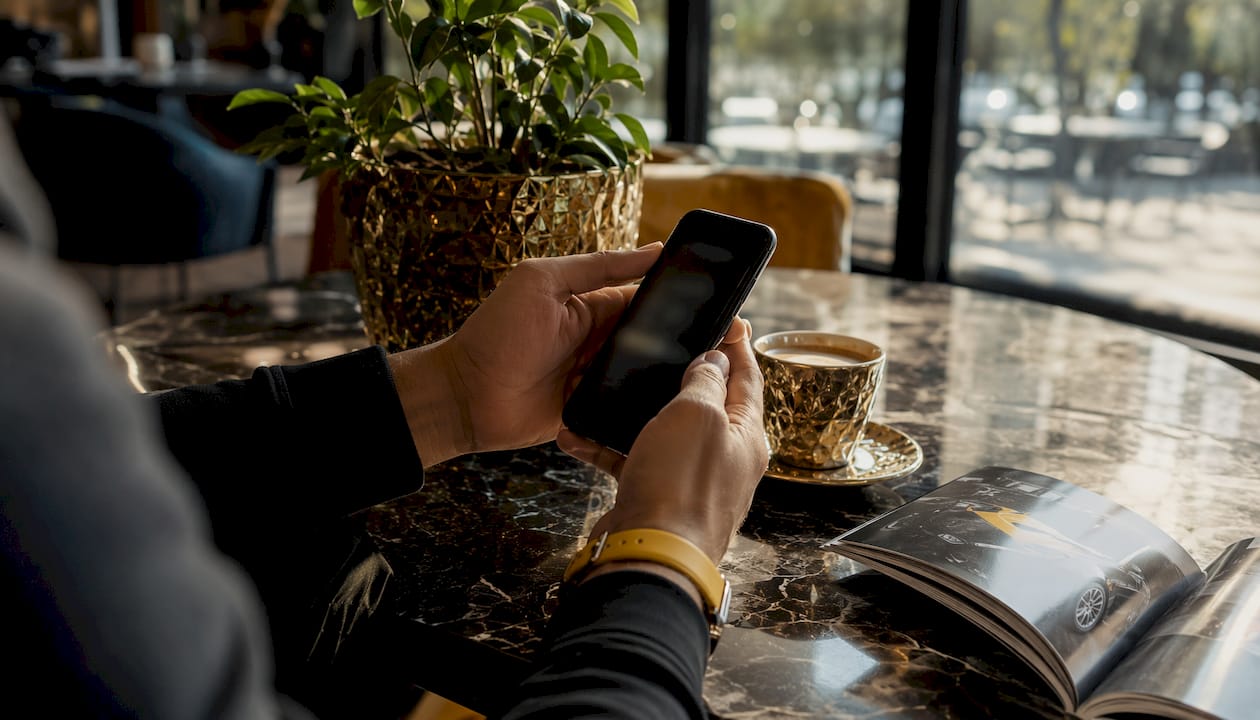 Hands scrolling smartphone at cluttered desk