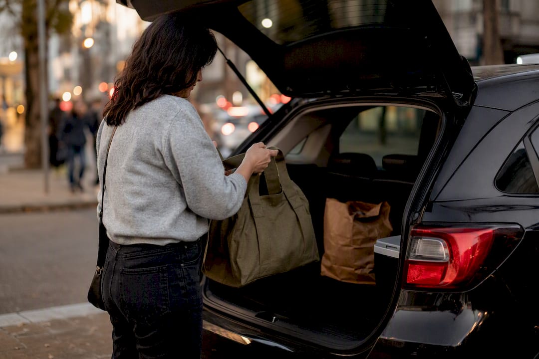 Hands loading groceries into subcompact SUV trunk