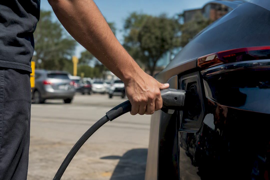 Hand plugging EV charger into vehicle port