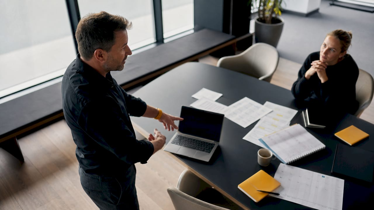 Två personer sitter tillsammans och planerar ett digitalt schema med hjälp av papper och penna.