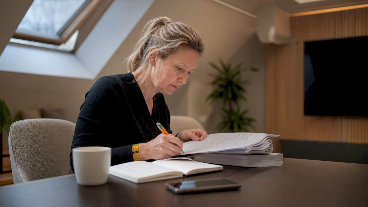 En chef sitter vid sitt skrivbord och går noggrant igenom företagets regelefterlevnadsdokument.