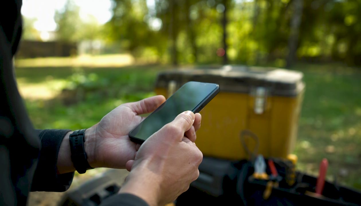 Händer som använder mobiltelefon för att rapportera direkt från fältet