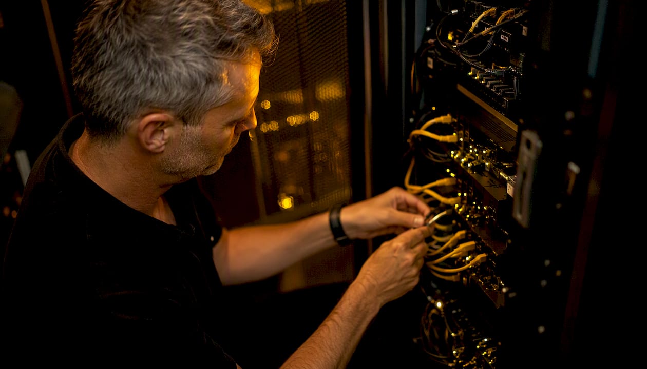 Någon arbetar med att installera och justera nätverksutrustning i ett datacenter.