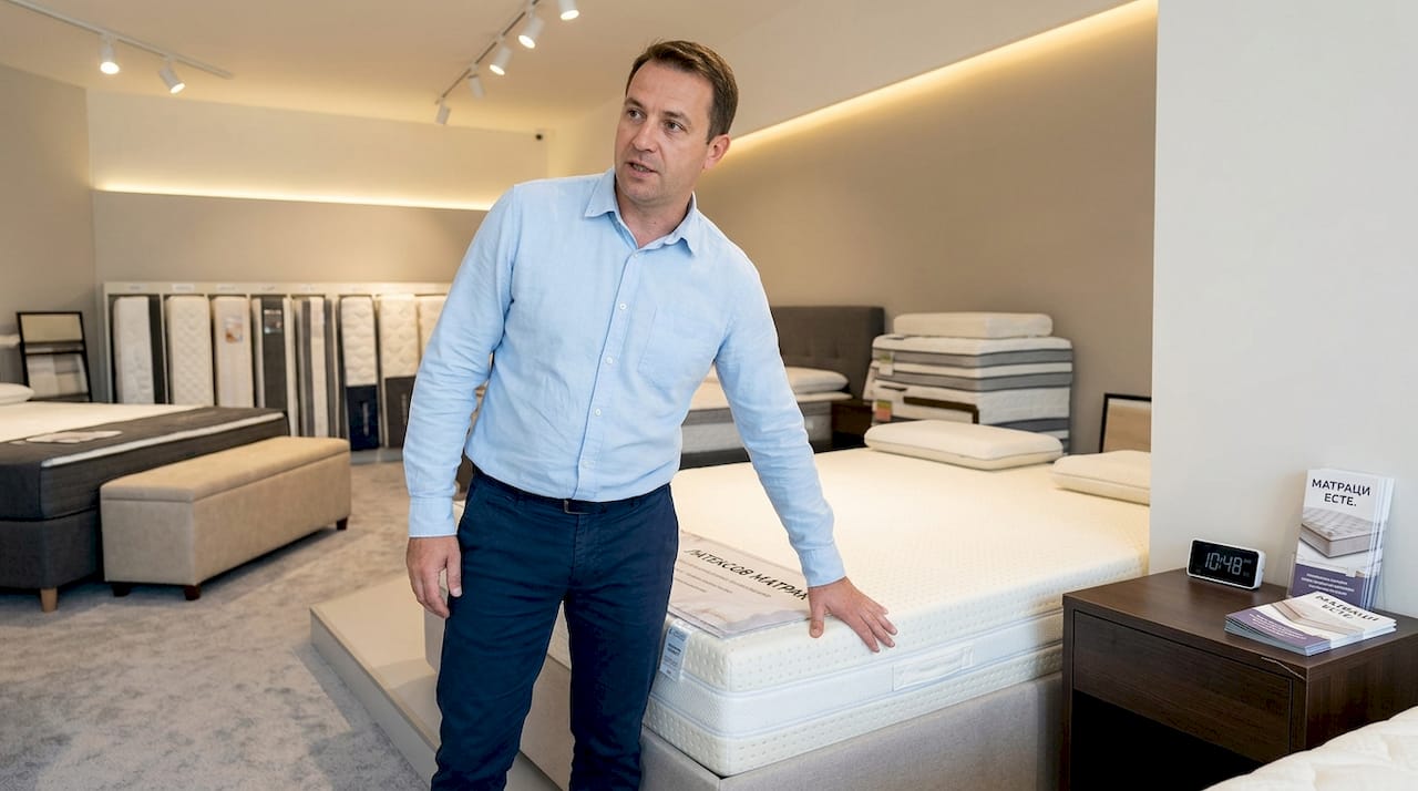 Консултантът в магазина показва колко еластичен и подскачащ е латексовият матрак, като го тества пред клиентите.