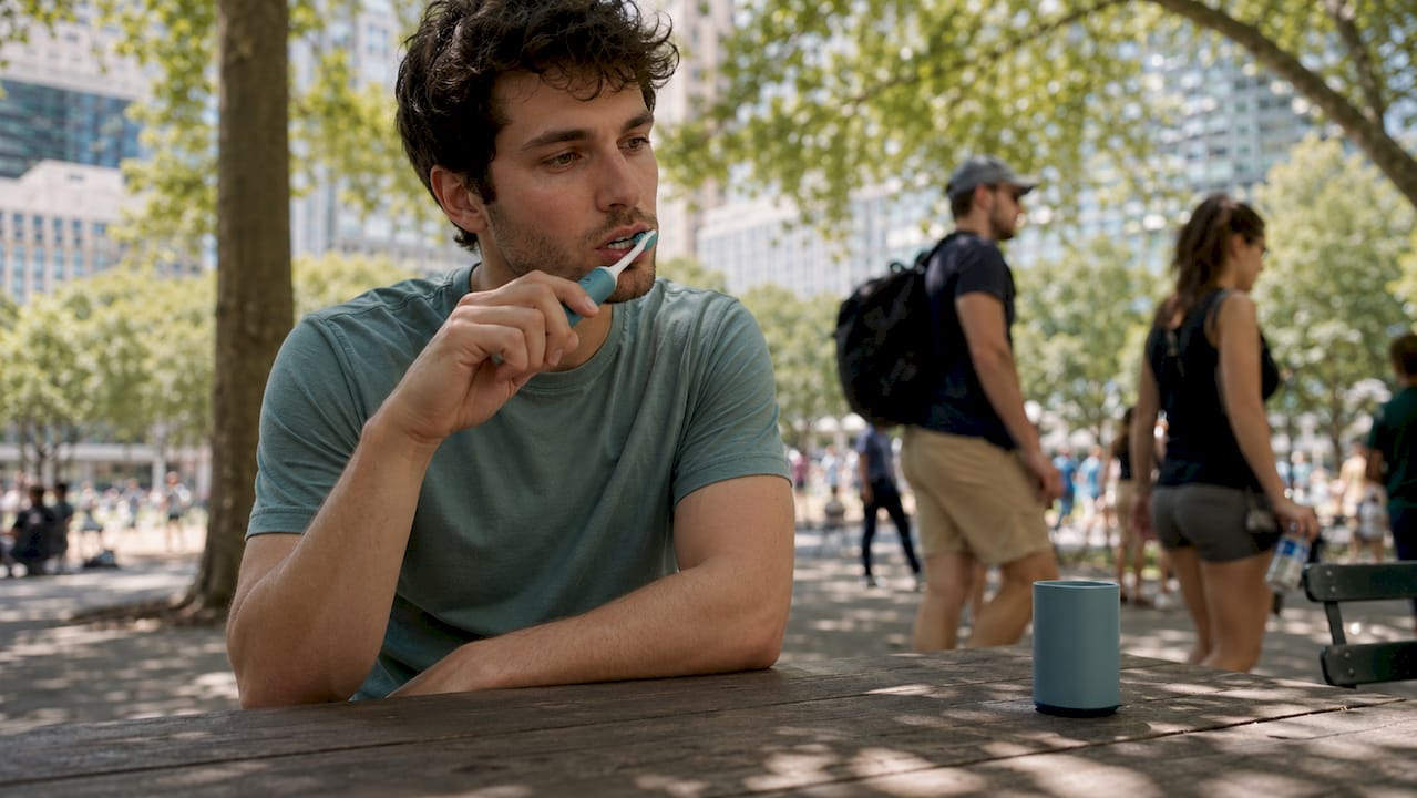 Young man gently brushing teeth outdoors