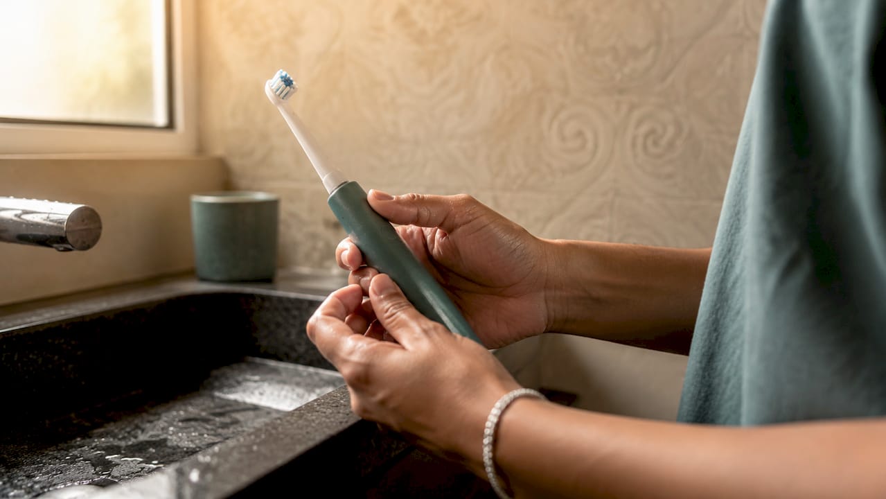 Hands holding electric toothbrush at brushing angle