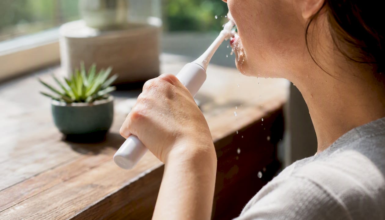 Hands brushing teeth with a sonic toothbrush
