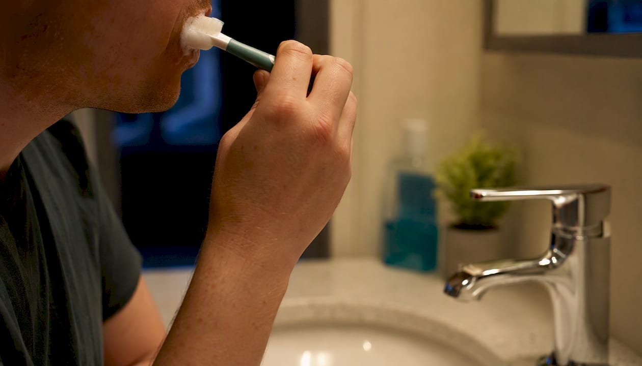 Person brushing teeth at sink