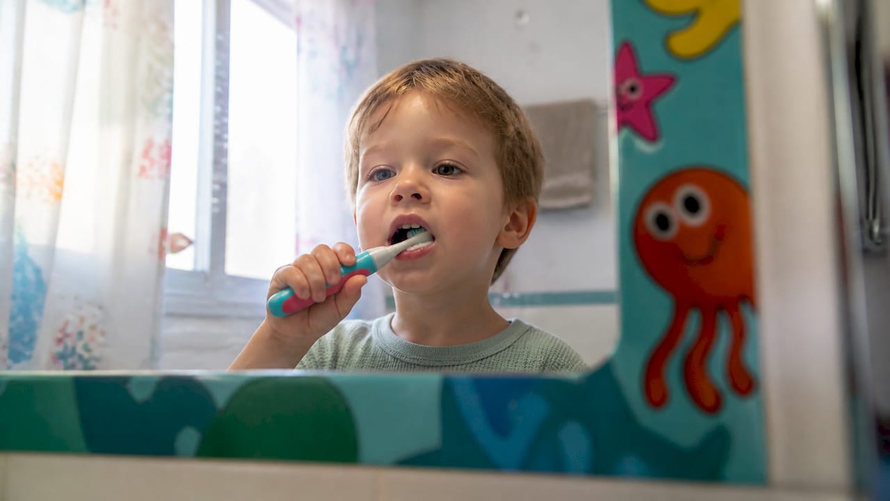Toddler brushing teeth with small electric toothbrush