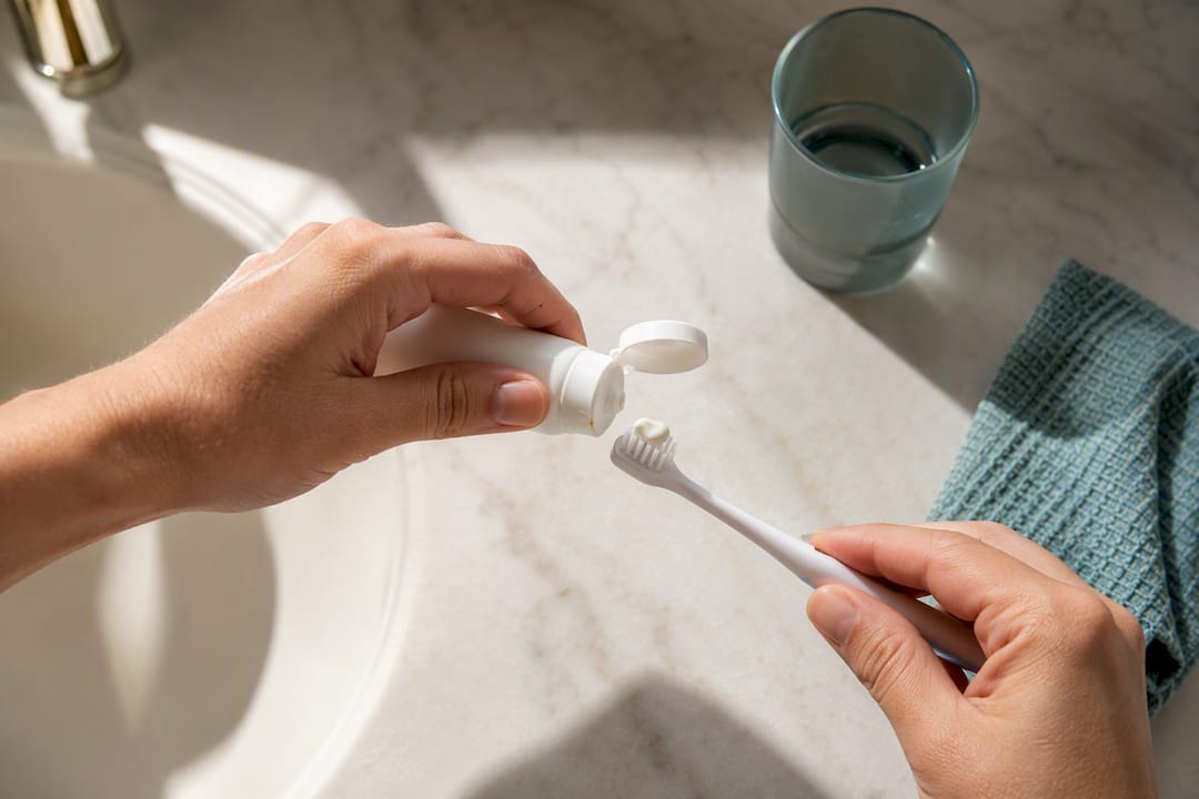 Parent applying toothpaste to child brush