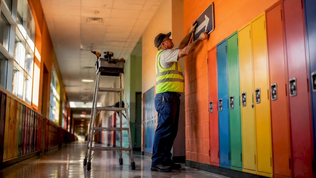 Maintenance worker installing hallway signage