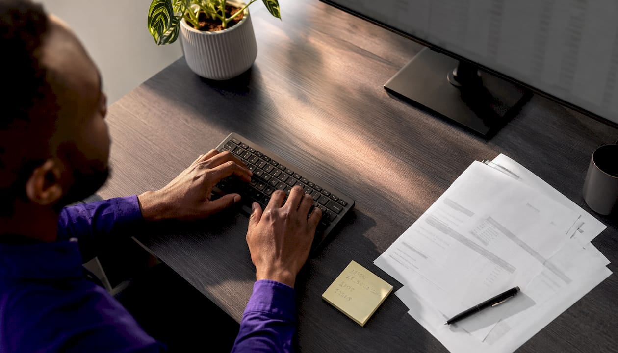 Hands typing on keyboard with invoices nearby