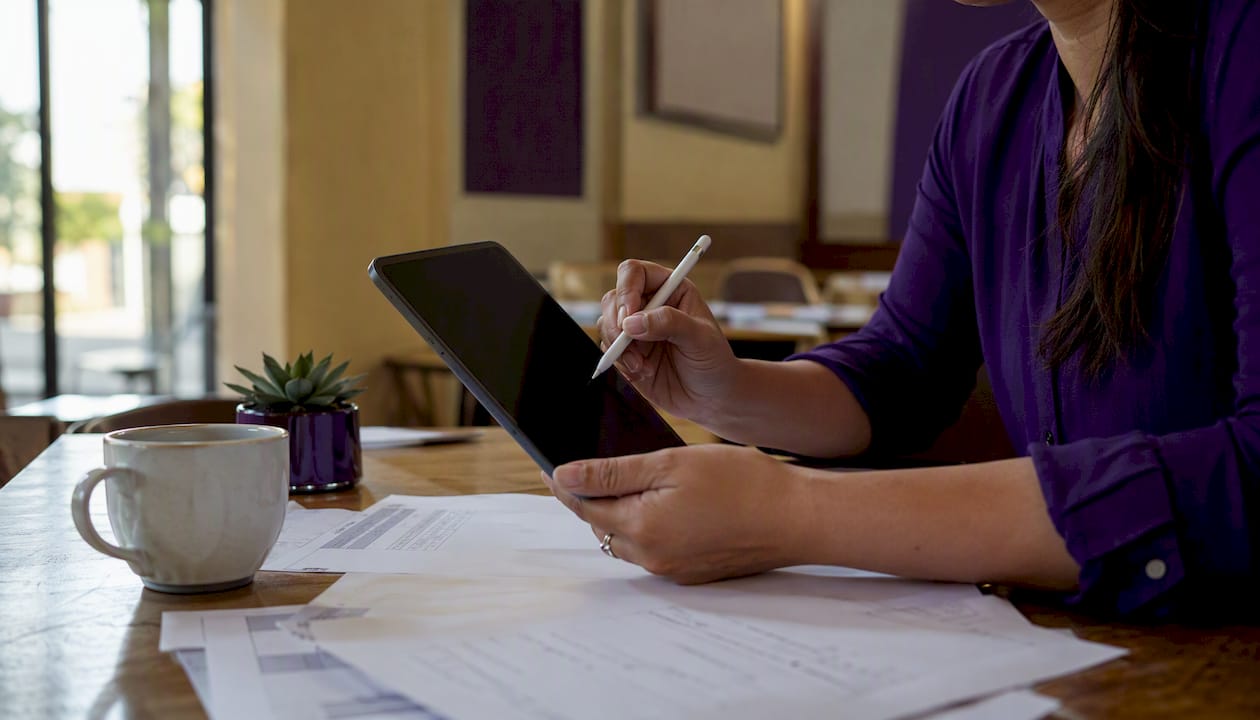 Hands using tablet with invoices and glasses