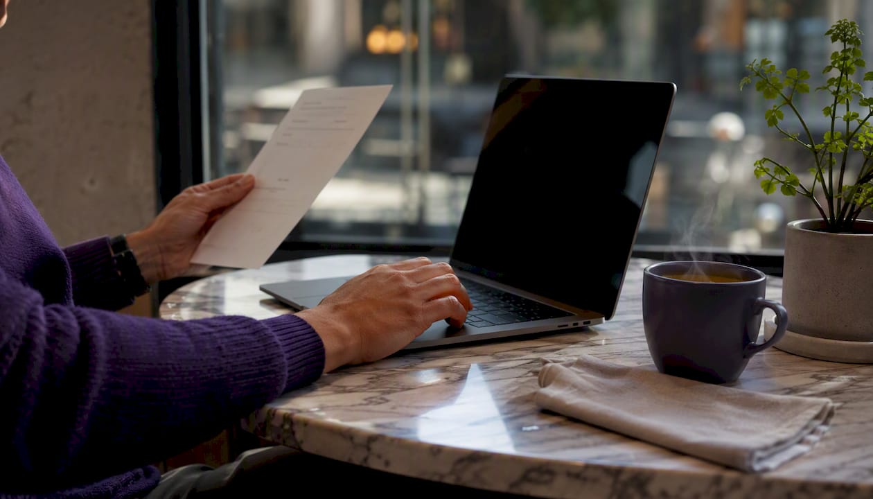 Hands reviewing invoice and laptop keyboard overhead
