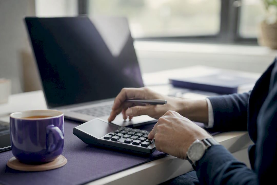 Hands adjusting calculator dial in finance workspace