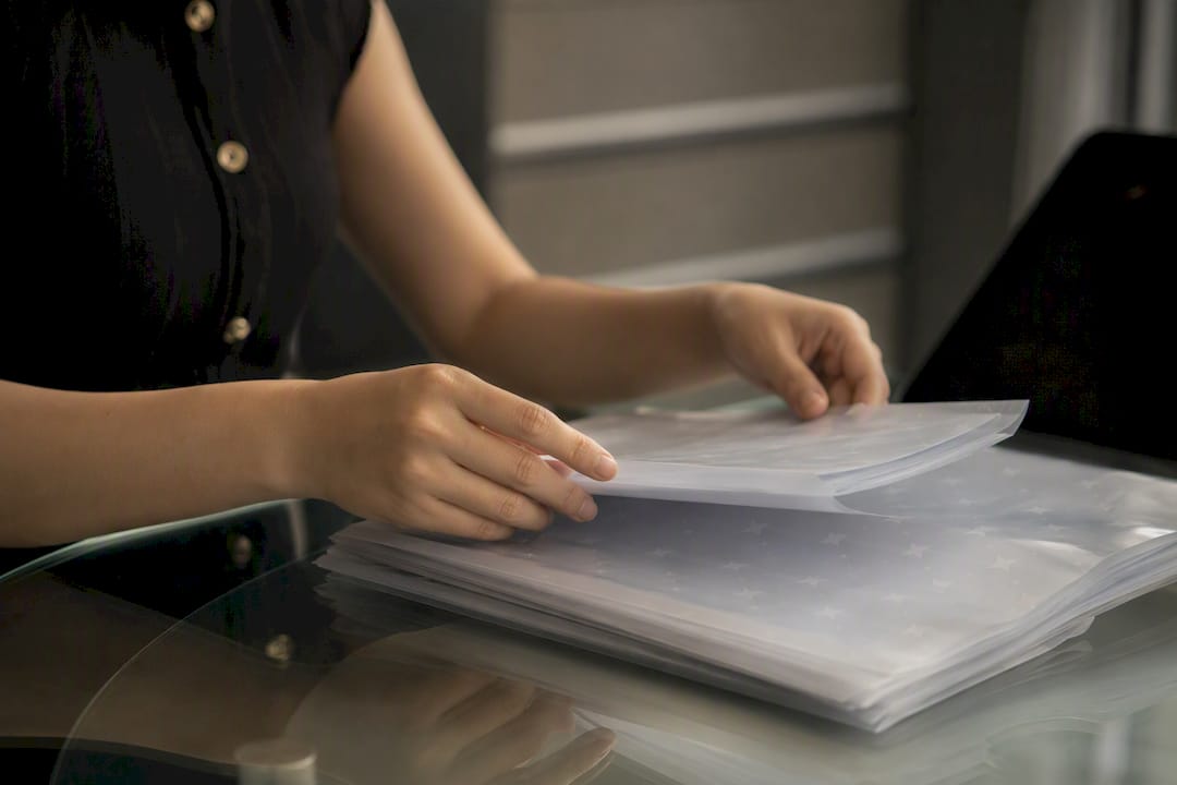 Hands organizing invoice sleeves at modern desk