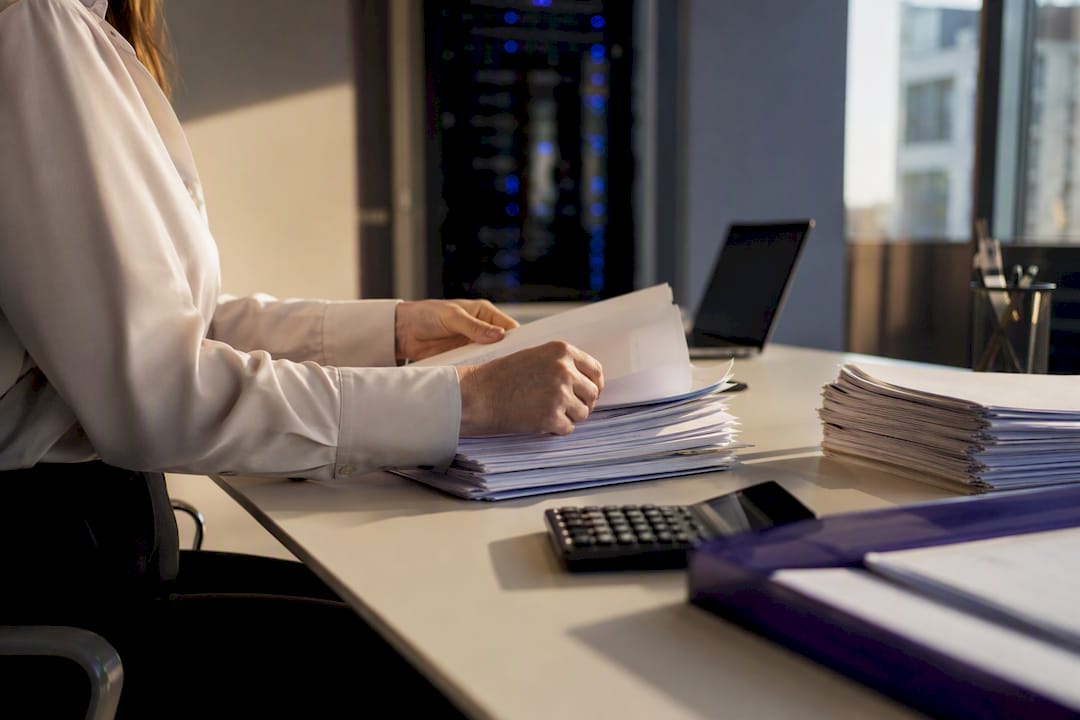 Hands moving invoices beside tech hardware