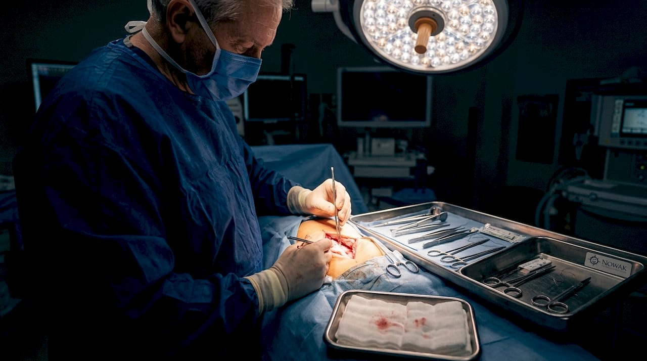 Surgeon repairing tendon in hospital operating room