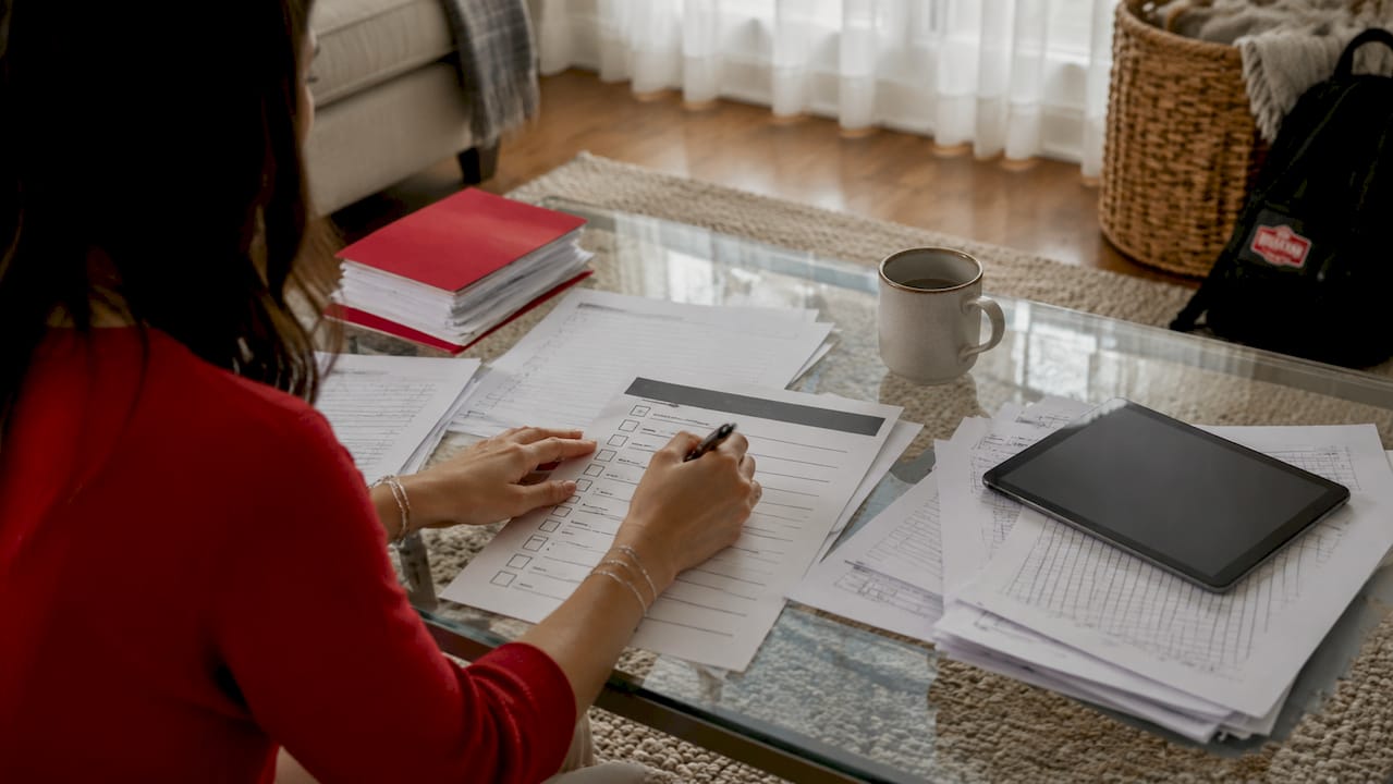 Hands marking moving checklist on kitchen table