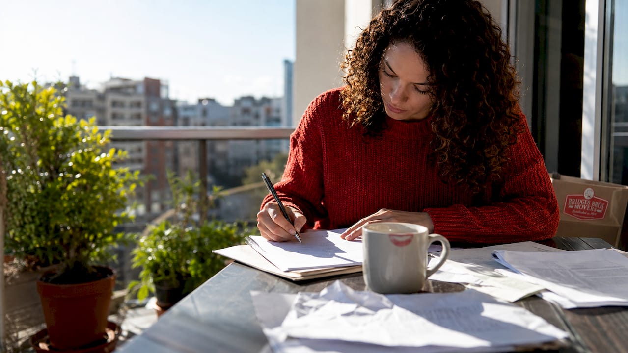 Woman writing landlord notice in apartment kitchen