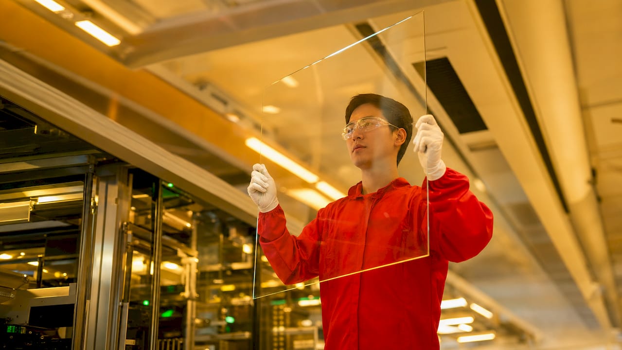 Technician inspecting substrate glass sheet in cleanroom
