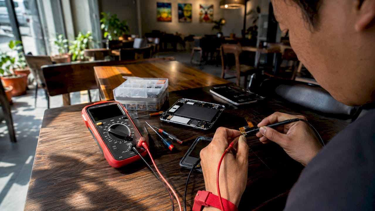 Hands testing smartphone LCD flex cable with tools