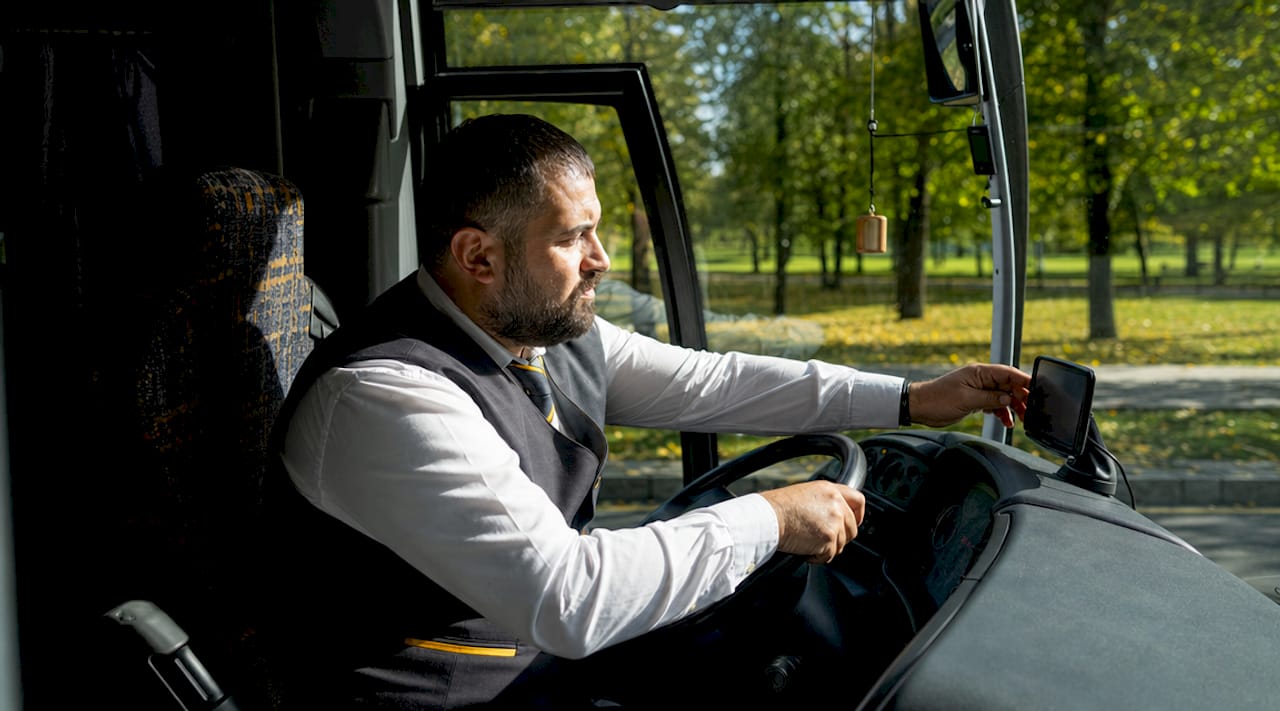Charter bus driver in cabin adjusting GPS