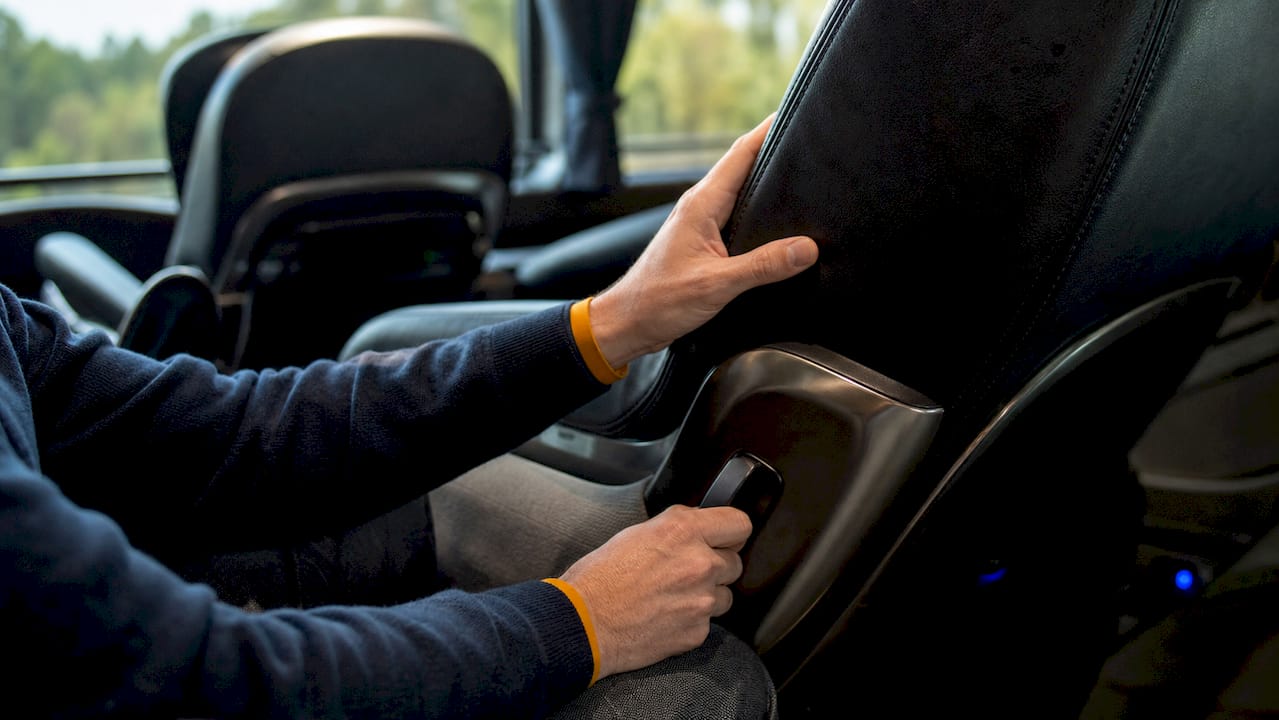 Hands adjusting VIP bus leather seat recline lever