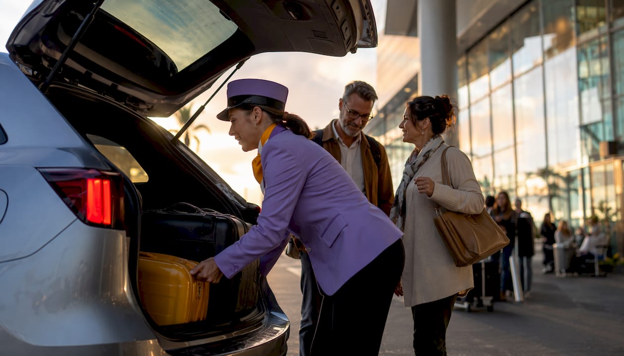 Driver helping passengers with luggage at airport