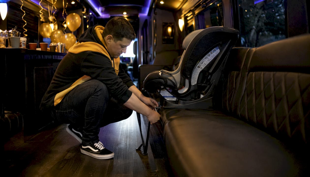 Man installing child car seat on party bus bench