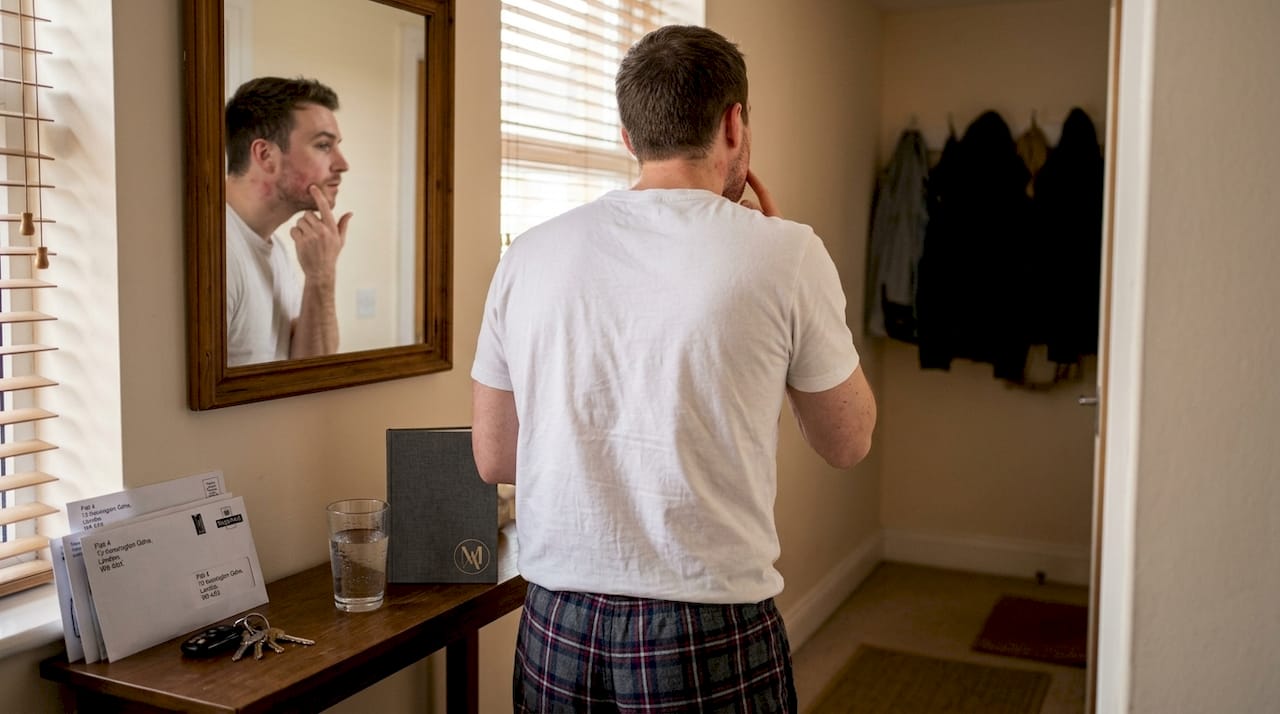 Man checks skin in hallway mirror