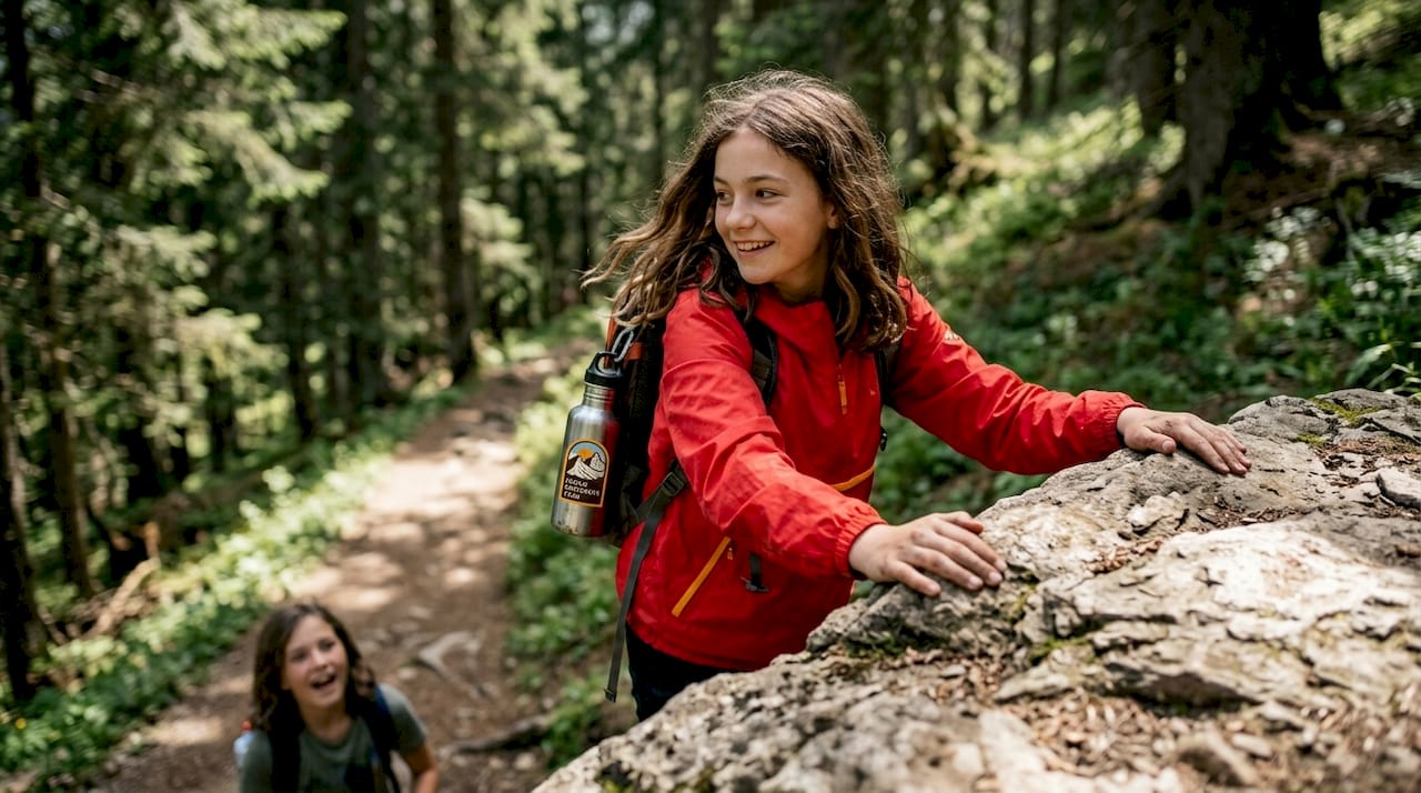 Teenage girl climbs rocky wooded trail