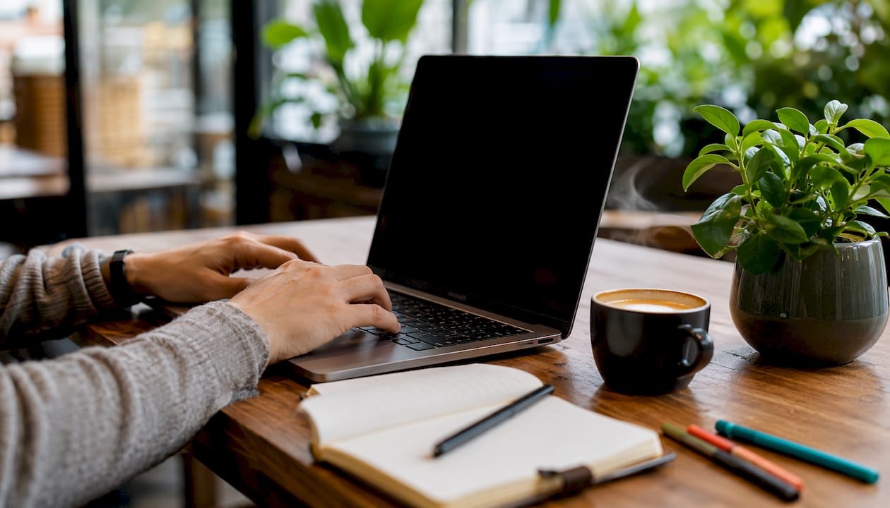 Hands typing on laptop engaging customers on social media