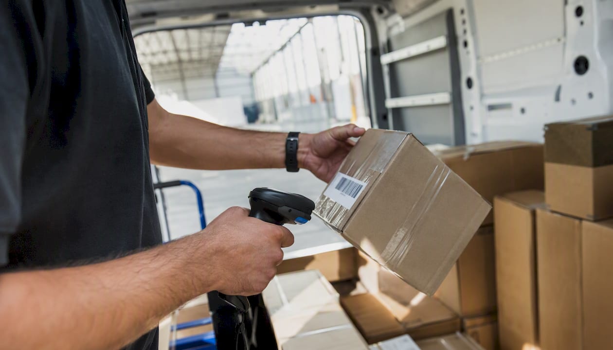 Courier scanning parcel inside delivery van